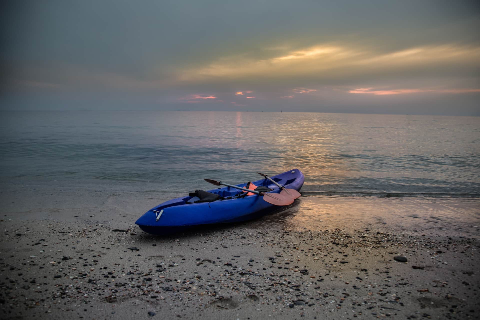 A kayak on a sandy beach at sunset