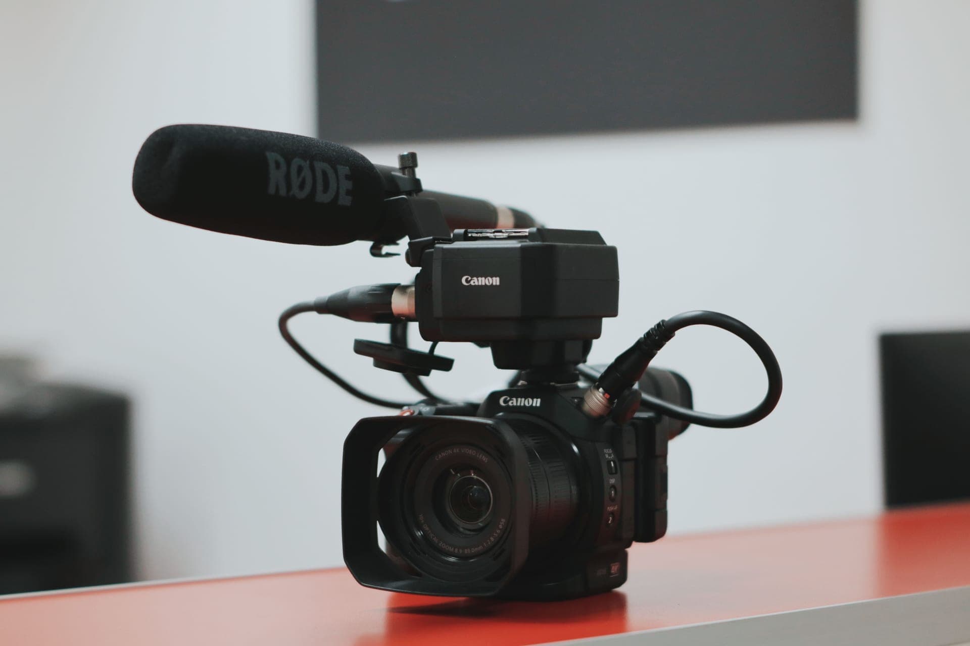 A video camera with a shotgun microphone mounted on a desk