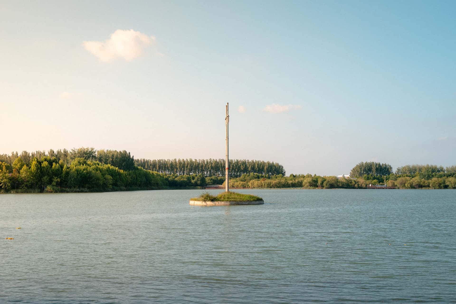 A calm lake with a solitary pole on a small island