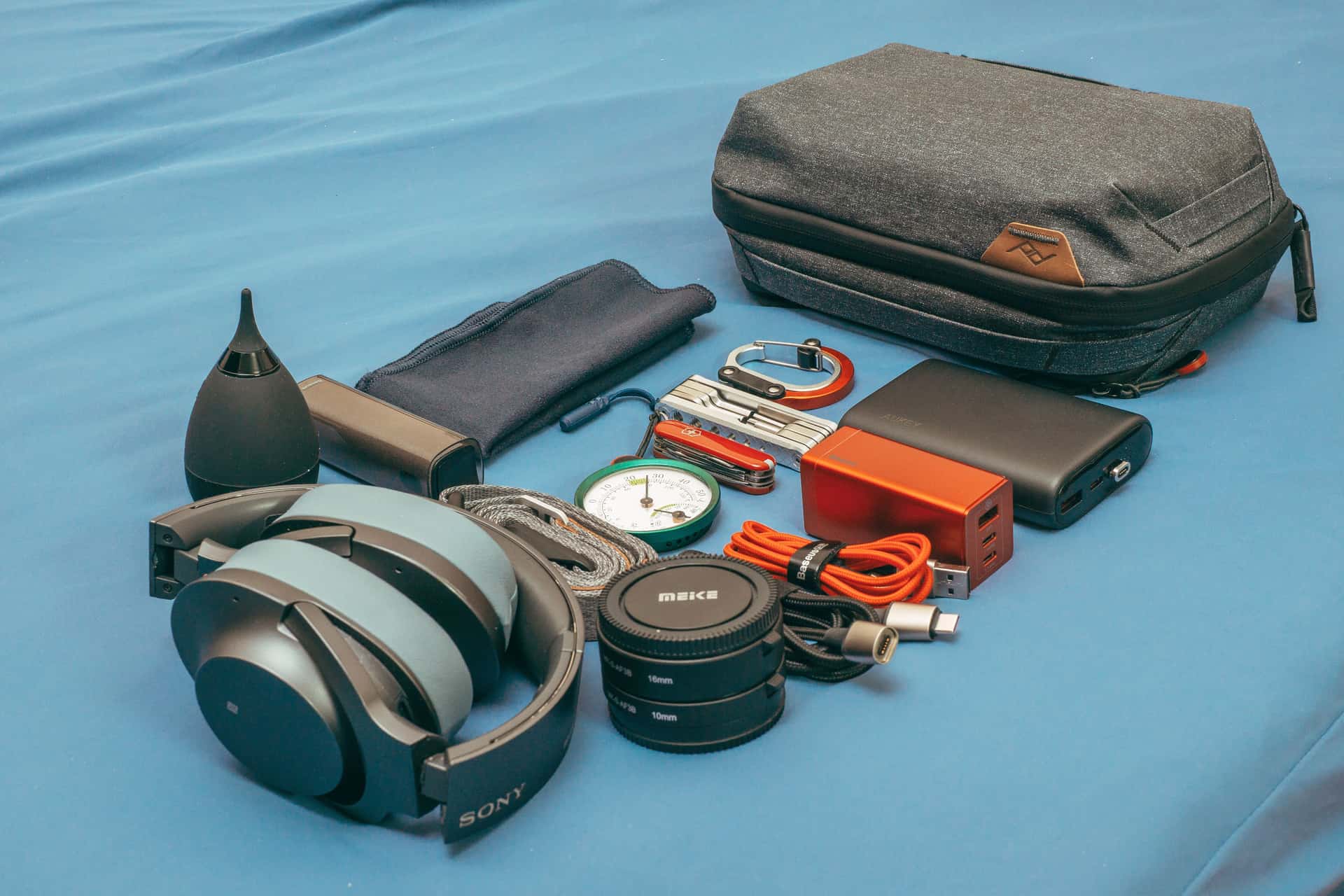 A flat lay of travel gear including a power bank, headphones and a compass