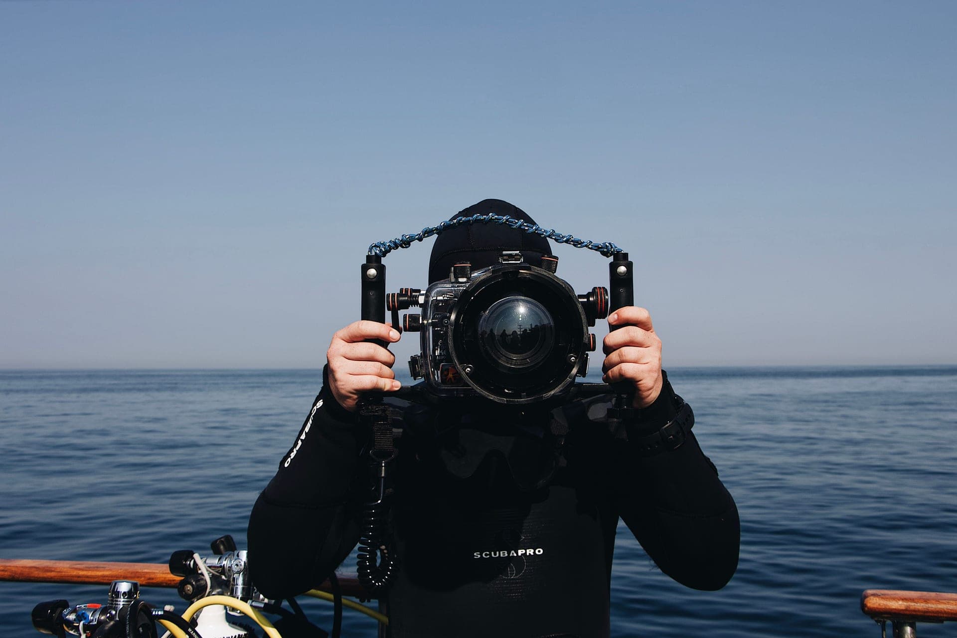 A diver holding an underwater camera setup on a boat